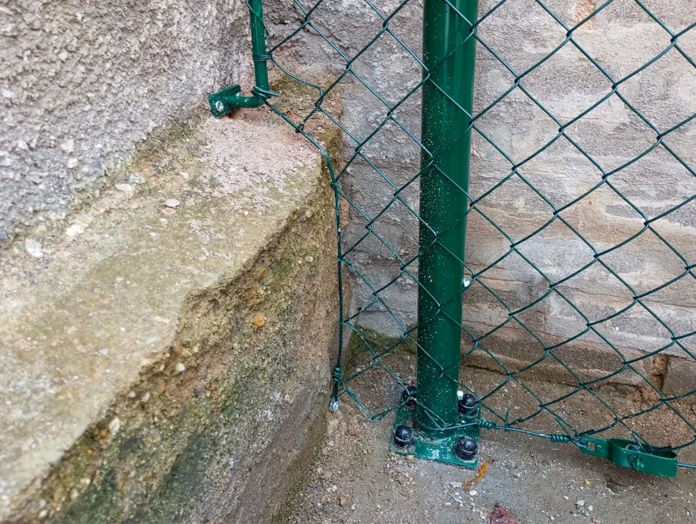 Zelený kulatý sloupek na patce přišroubované k betonu, se čtyřhranným pletivem, realizace Slaný